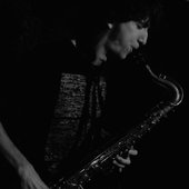 quetzal playing her saxophone in black and white