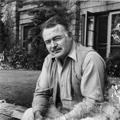 Ernest Hemingway sits in front of a building, Ketchum, Idaho.jpg